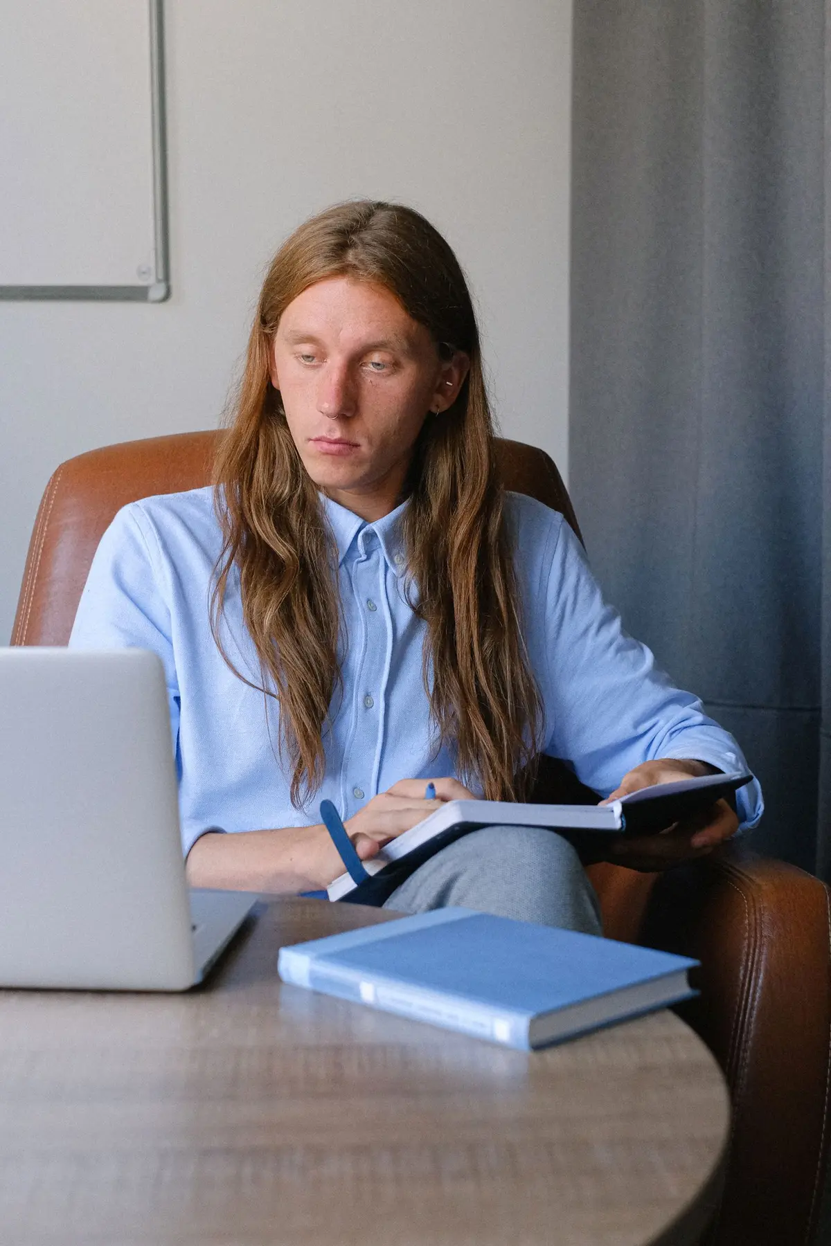 A young man using a laptop with an open planner on his lap